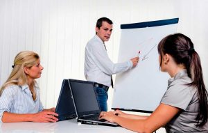Un formateur sur un paperboard avec deux collaboratrices