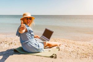 Freelance en portage salarial avec un ordinateur heureuse à la plage